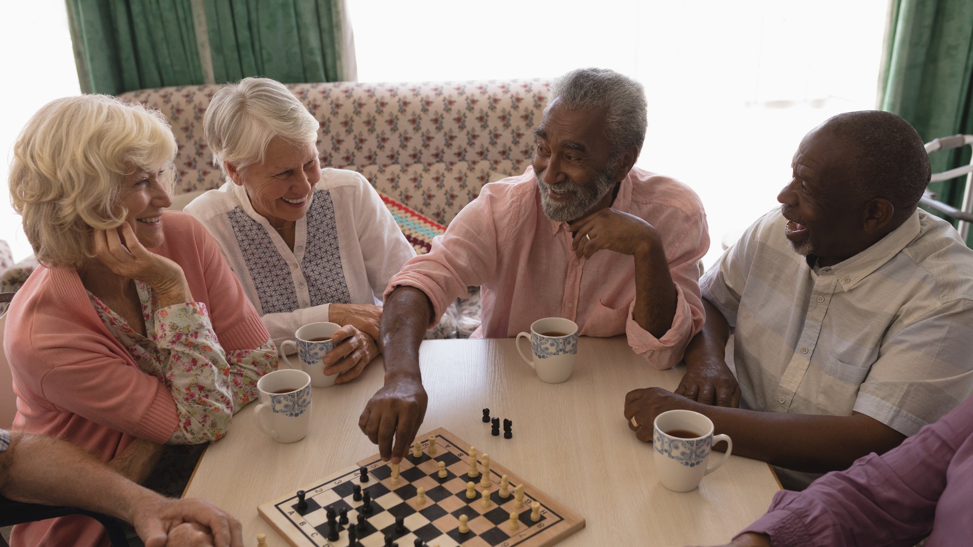 Senior friends enjoying a game of chess together over tea